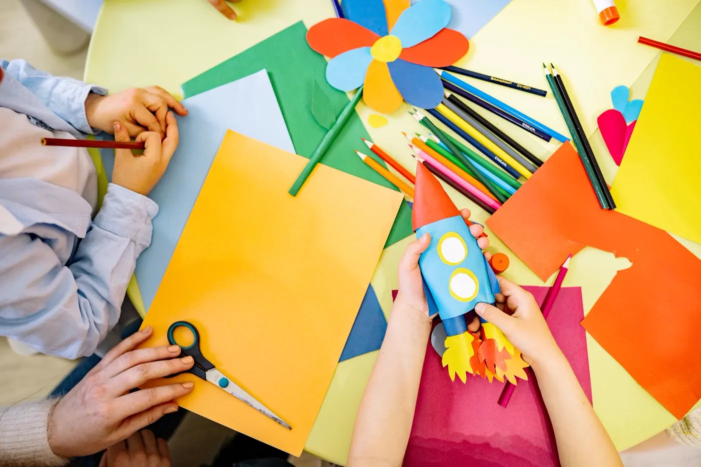 Children's hands making colorful paper crafts together